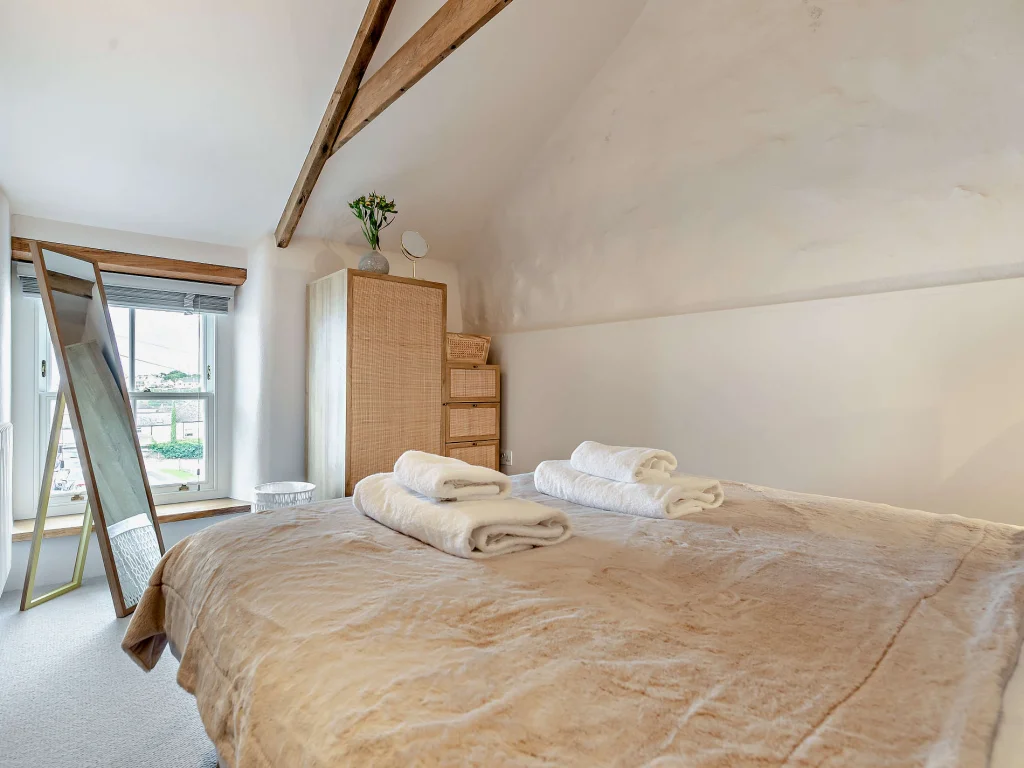 King bedroom with vaulted beamed ceiling and wicker wardrobe