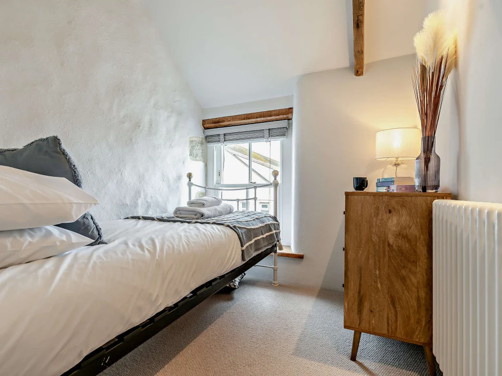 Single bedroom with metal bedstead and sloped ceiling